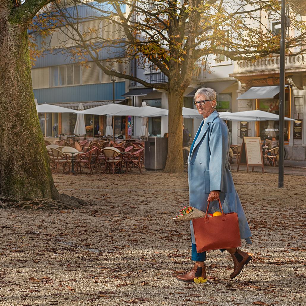 Dame spaziert mit Einkaufstasche durch den herbstlichen Park